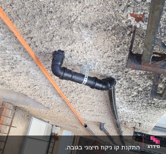צינור שחור מחובר לקיר עם תושבת מתכת
